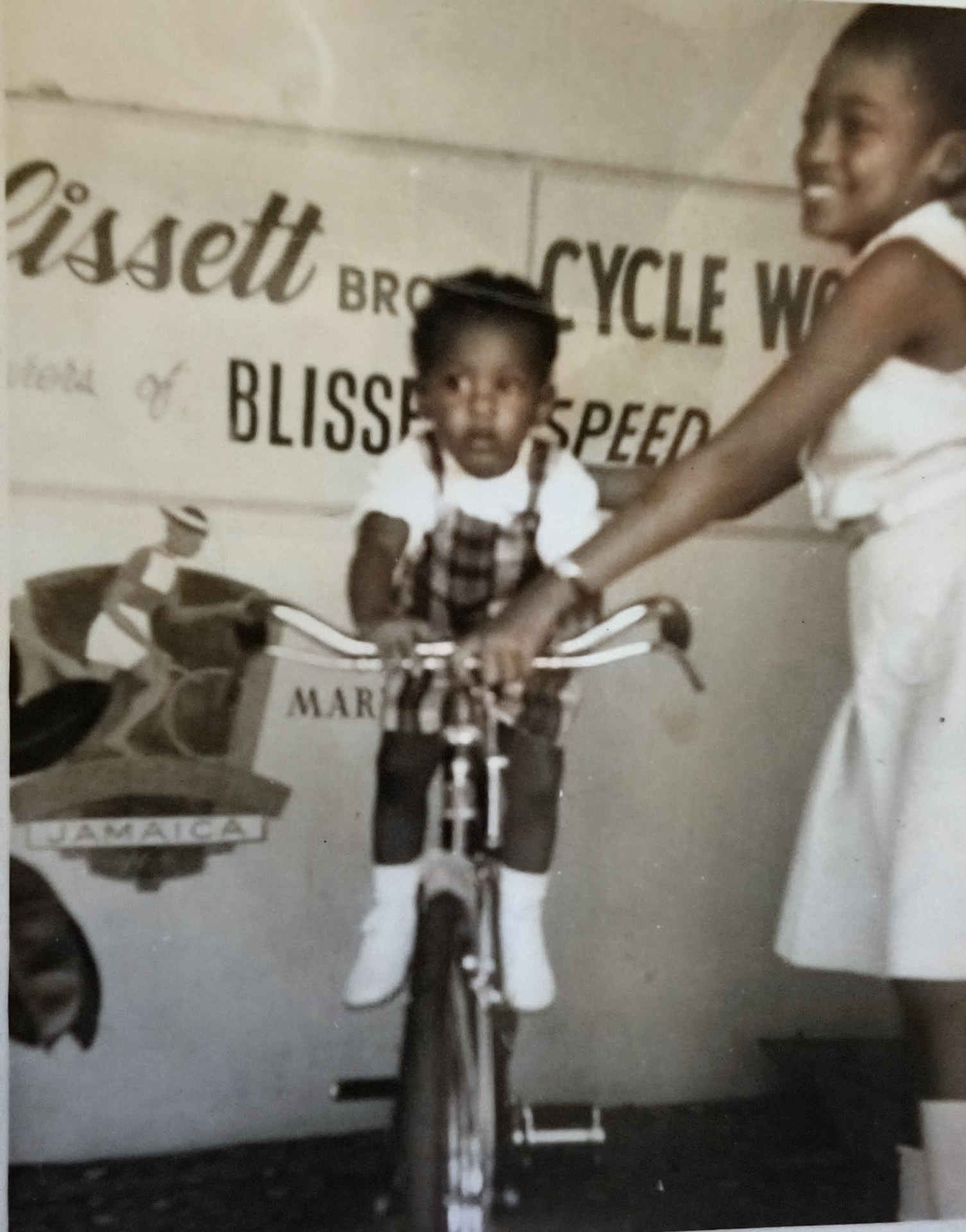 Original black-and-white photograph of Pat Blissett and her younger brother Brent with a bicycle at Blissett Bros. Cycle Works Ltd.